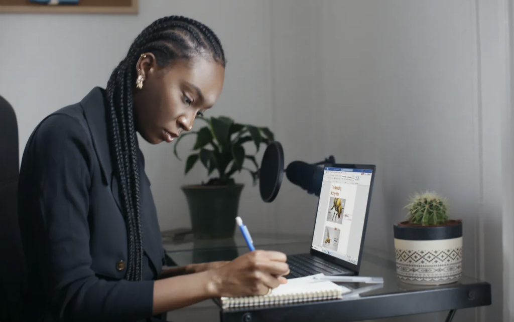 A woman writing on a laptop, finding her self-worth through work while feeling disconnected from her surroundings.