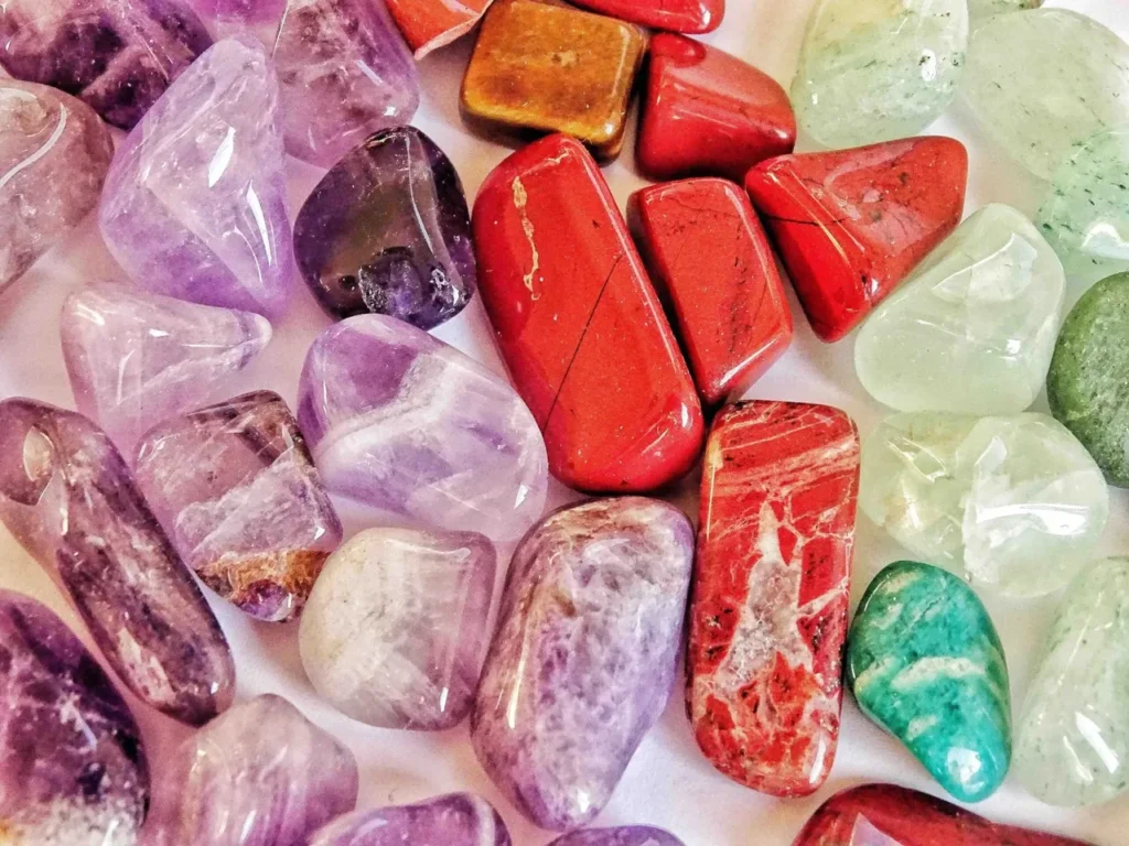 A variety of healing stones and gemstones are arranged on a white surface.