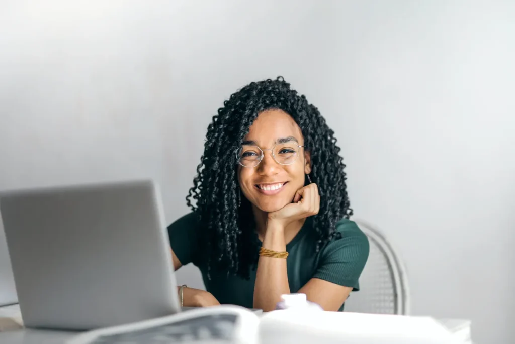 A young woman with curl sitting at a desk with a laptop, finding ways to balance work and life through helpful tips.