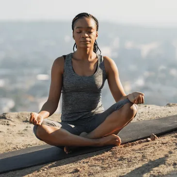 A woman is meditating on top of a mountain, symbolizing an empowering journey about us.