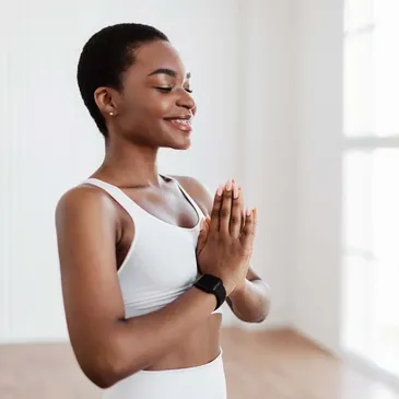 A black woman practicing yoga in a white room, highlighting the important and powerful representation of diversity in wellness.