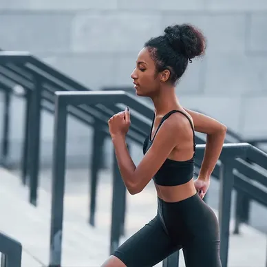 About Us: A young woman engaging in SYM exercise by jogging on a set of stairs.