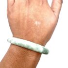 A woman's hand is holding a Jade Bangle Bracelet.