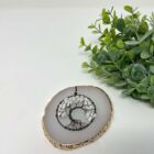 A Howlite Tree of Life Pendant on a white marble slab.