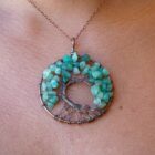 A woman is wearing a Green Aventurine Tree of Life pendant with a green aventurine.