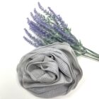 A Rose Loofah - Grey ruffle with lavender flowers next to it.