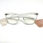 A pair of Blue Light Blocking Photochromic Glasses- Clear on a white surface with a pink rock.