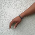 A person's hand is leaning against a Large Hematite Gemstone Bead Bracelet.