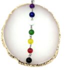 A 7 Chakra Pendant Necklace with multi colored beads on a gold plate.