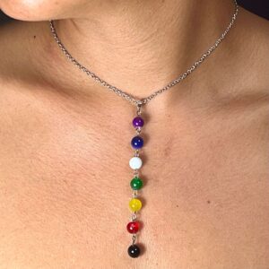 A woman wearing a 7 Chakra Pendant Necklace - Silver Chain with different colored stones.