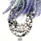 A Pink Zebra Stone 108 Mala Gemstone Bead Necklace featuring a lotus flower pendant made of pink zebra stone.