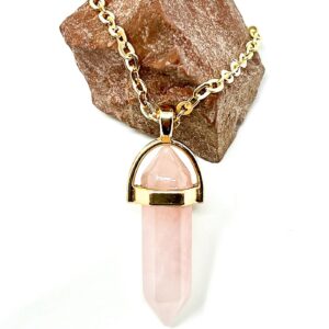 Love's Embrace: Rose Quartz Heart Necklace featuring a Rose Quartz pendant on a rock.