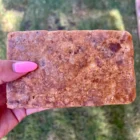 A person displaying a bar of African Black Soap.