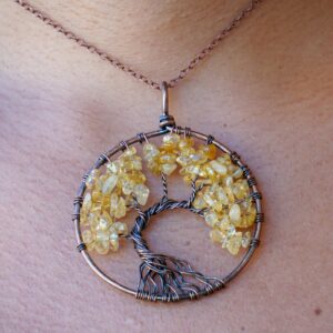 A woman is wearing a Citrine Tree of Life Pendant.