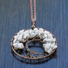 A white Howlite Tree of Life Pendant on a wooden table.