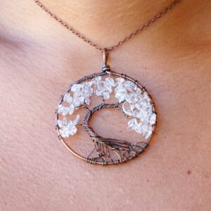 A woman is wearing a Clear Quartz Tree of Life Pendant.