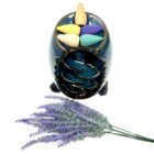 A Turquoise Ceramic Waterfall Backflow Incense Burner with Mixed Incense Cones, Sticks & Sage next to a lavender flower.