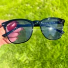 A person holding a pair of Blue Light Blocking Photochromic Transition Glasses- Black in the grass.