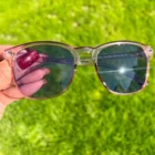 A person holding a pair of Blue Light Blocking Photochromic Glasses- Pink in the grass.