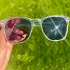 A person holding a pair of Blue Light Blocking Photochromic Glasses- Clear in the grass.