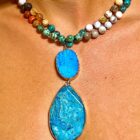 A woman is wearing a Multi Stone 108 Mala Gemstone Bead Necklace with Pendant.