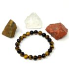 A Natural A+ Yellow Tiger Eye gemstone bracelet with stones and a rock.