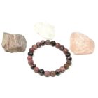 A Matrix Rhodonite Gemstone Bracelet with a rock next to it.