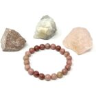 A Pink Rhodonite Gemstone Bracelet 8mm with a rock next to it.