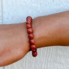 A woman's wrist adorned with a Red Goldstone Gemstone Bracelet.