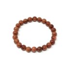 A Red Goldstone Gemstone Bracelet with red jasper beads on a white background.