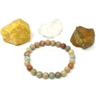 An Aqua Terra (Serpentine) gemstone bracelet with Aqua Terra stones and a rock next to it.