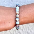 A woman's wrist adorned with a Blue Sea Sediment Jasper Gemstone Bracelet.