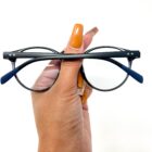 A person holding a pair of Blue Light Blocking Photochromic Glasses Round Circle Lenses - Black & Blue eyeglasses.