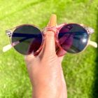 A person holding up a pair of Blue Light Blocking Photochromic Glasses Round Circle Lenses in Pink/Blue & Cream.