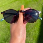 A person holding a pair of Blue Light Blocking Photochromic Glasses Round Circle Lenses - Grey/ Red/Blue.