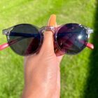 A person holding a pair of Blue Light Blocking Photochromic Glasses with round circle lenses in the grass.