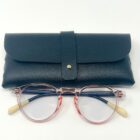 A pair of Blue Light Blocking Photochromic Glasses Round Circle Lenses - Pink/ Blue & Cream reading glasses with a black leather case.