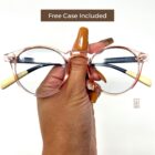 A person holding up a pair of Blue Light Blocking Photochromic Glasses Round Circle Lenses - Pink/ Blue & Cream with the words "free case included.