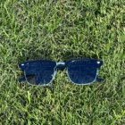 A pair of Blue Light Blocking Photochromic Glasses Vintage Style - Metal Frame- Black Temples laying on the grass.