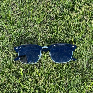 A pair of Blue Light Blocking Photochromic Glasses Vintage Style - Metal Frame- Black Temples laying on the grass.