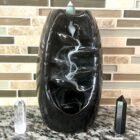 A Black Ceramic Waterfall Backflow Incense Burner with Mixed Incense Cones, Sticks sitting on a counter.