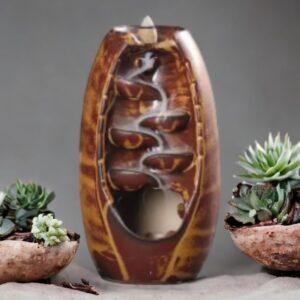 A Tan Ceramic Waterfall Backflow Incense Burner with Mixed Incense Cones, serving as home decor, next to it.