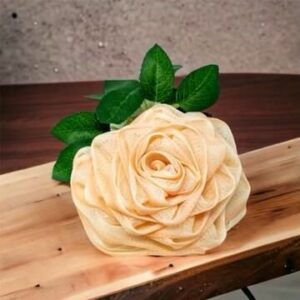 A Rose Loofah- Peach is sitting on top of a wooden table.