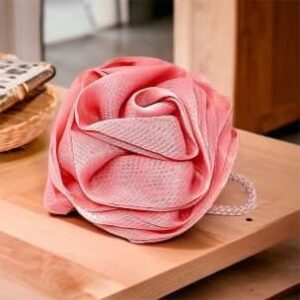 A Rose Loofah- Natural Loofah Sponge- Pink sitting on top of a wooden table.