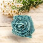 A teal Rose Loofah- Blue&White- Bath- Body- Self Care is sitting on a wooden table, adding a touch of self-care elegance to the blue and white theme.