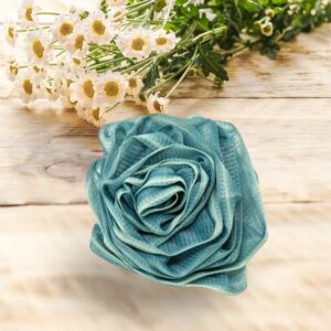 A teal Rose Loofah- Blue&White- Bath- Body- Self Care is sitting on a wooden table, adding a touch of self-care elegance to the blue and white theme.