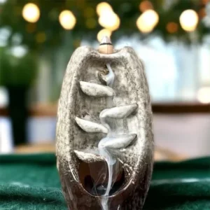 A Tan Ceramic Waterfall Backflow Incense Burner with Mixed Incense Cones sitting on top of a table.