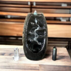 A black Ceramic Waterfall Backflow Incense Burner with Mixed Incense Cones, Sticks on a wooden table.