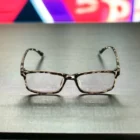 A pair of Blue Light Blocking Photochromic Glasses Rectangle Lenses - Leopard sitting on a table in front of a television.