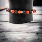 A black Gemstone Crystal Bracelet, Carnelian, Lava and Silver Stainless Steel Spacers 6mm hat with red beads on it.